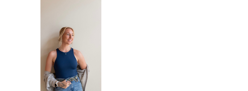Lottie Evans in a blue top, standing in front of a pale wall