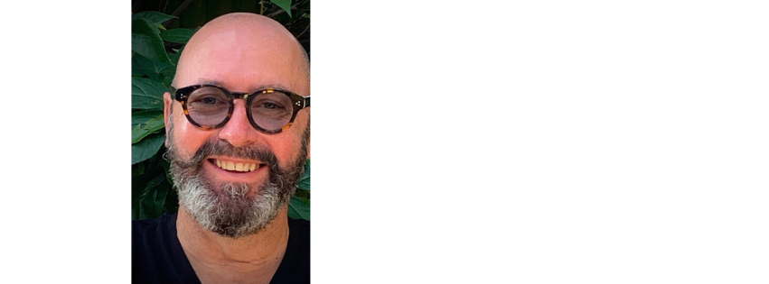 Tim Johnson in glasses, with a beard, smiling at the camera
