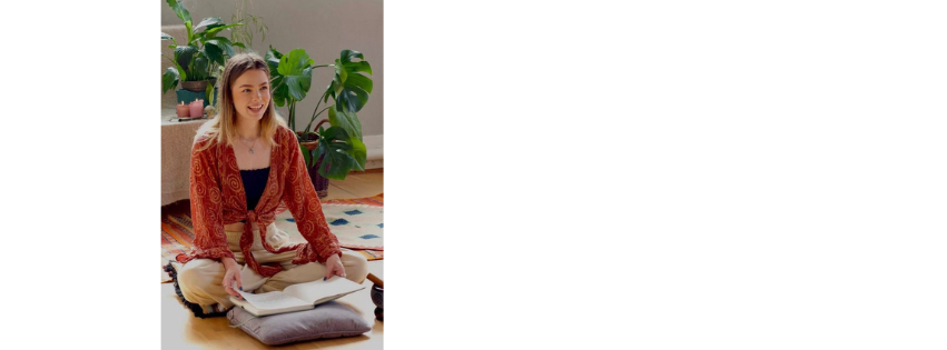 Lottie Hall seated in a bright room beside a large houseplant