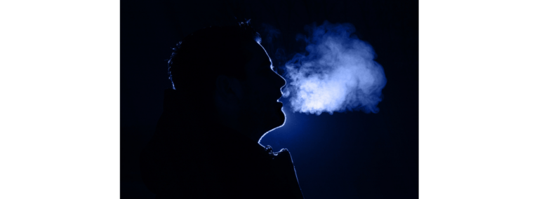 A silhouetted profile exhaling a cloud of white vapour against black