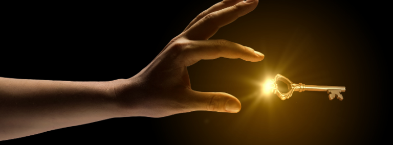 A hand reaching towards a small glowing key suspended in darkness