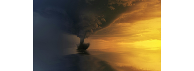 A dark funnel cloud twisting down through a golden sky
