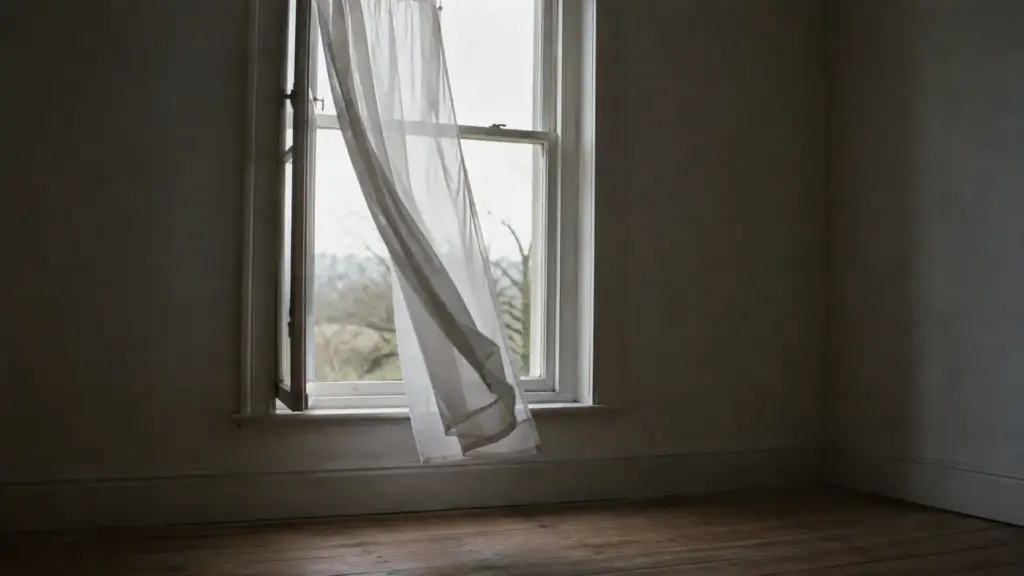 An open window with a net curtain lifting in the breeze