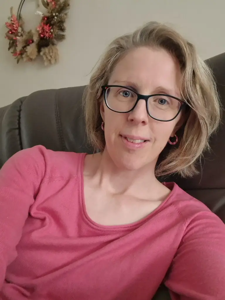 Alison McEvoy in a pink top and glasses, smiling at the camera