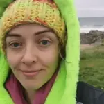Catriona Byrne outdoors in a green and orange knitted hat