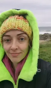 Catriona Byrne outdoors in a green and orange knitted hat