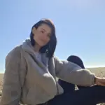 Kristina Pyrtova in a fleece jacket, sitting by the sea