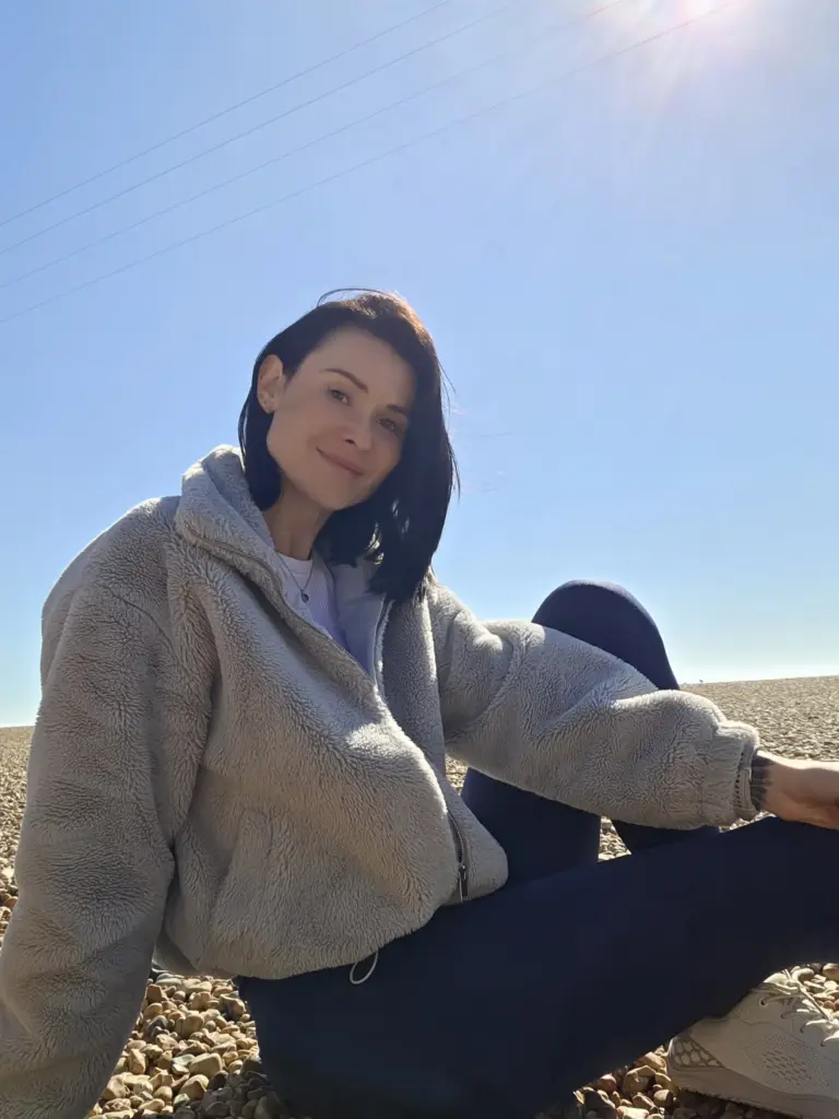 Kristina Pyrtova in a fleece jacket, sitting by the sea